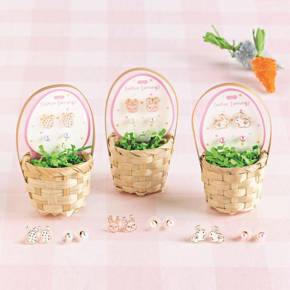 Three small woven baskets with decorative items on a pink background