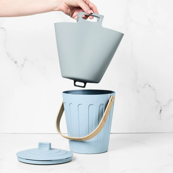 Light blue trash bin with a lid and handle on a white background