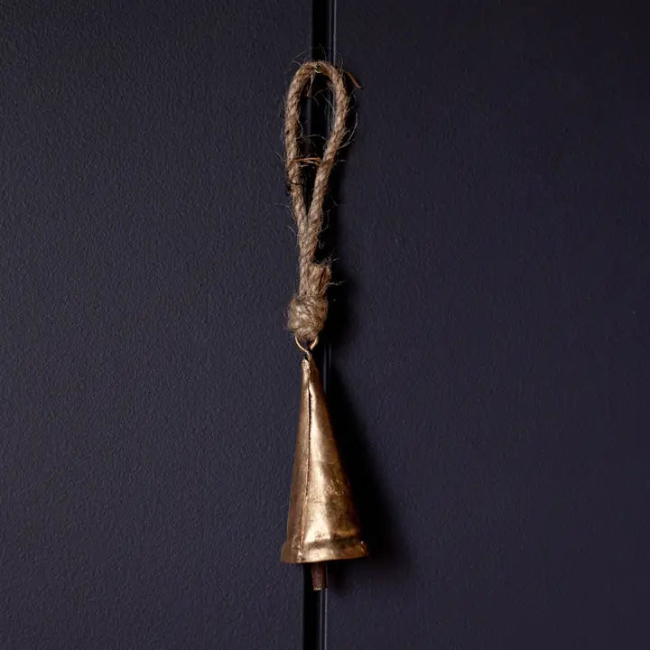 Small tapered bronze bell ornaments hanging together on a Christmas tree with greenery and red velvet ribbon.