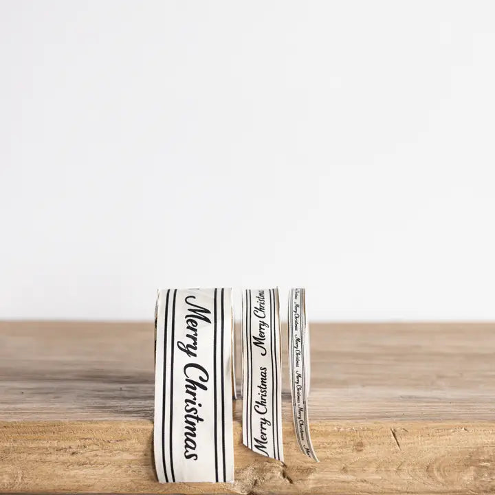 Small, medium and large cream Christmas ribbon spools with black cursive Merry Christmas lettering displayed upright.