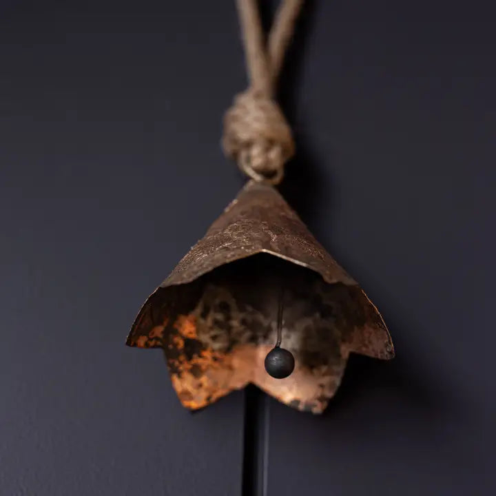 Close-up underside view of bronze scalloped iron bell ornament showing the clapper and aged interior finish.