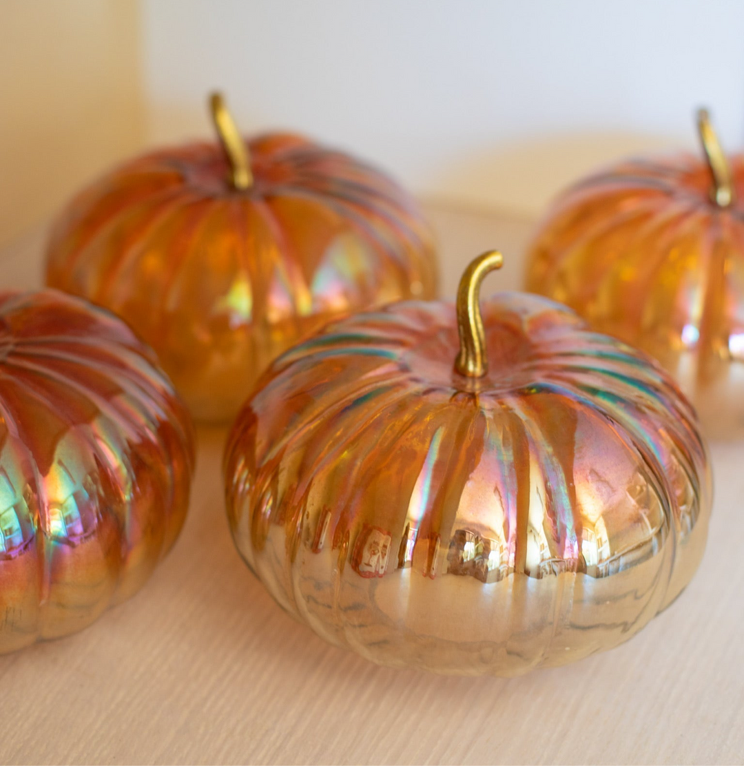 Iridescent glass pumpkins with gold stems on a neutral background