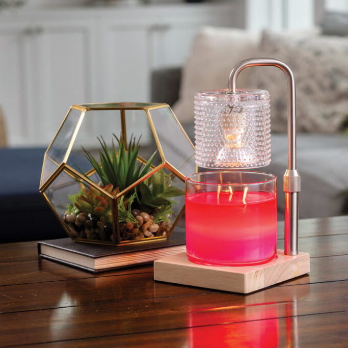 Decorative candle holder with pink candle on a wooden table in a living room setting.