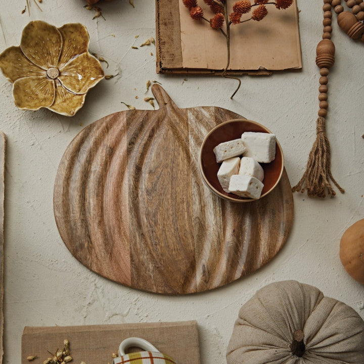 Autumn-themed decor with pumpkins, leaves, and a cup on a textured surface.