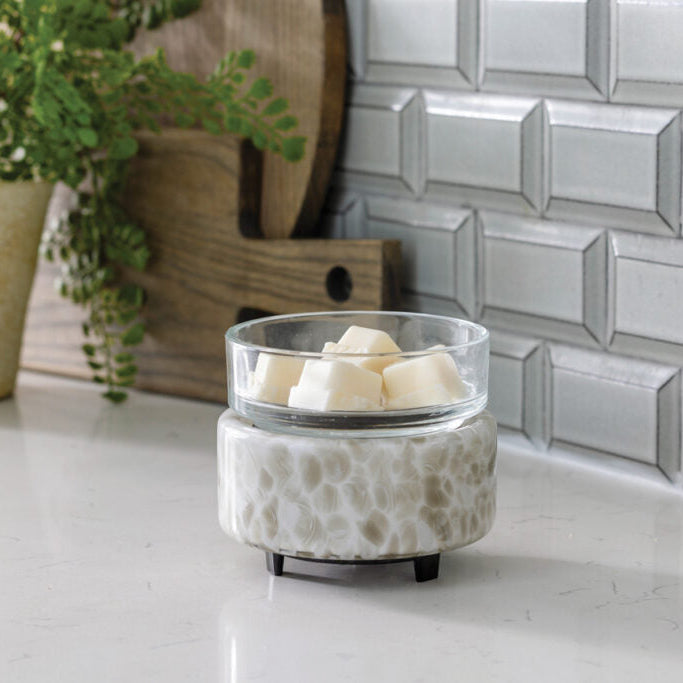Ceramic wax warmer with candles on a countertop next to a plant and decorative items.
