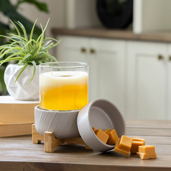 Glass of orange juice on a wooden coaster with fudge pieces on a kitchen counter.