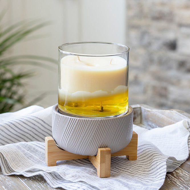 Glass candle with a wooden base on a white cloth with a blurred background