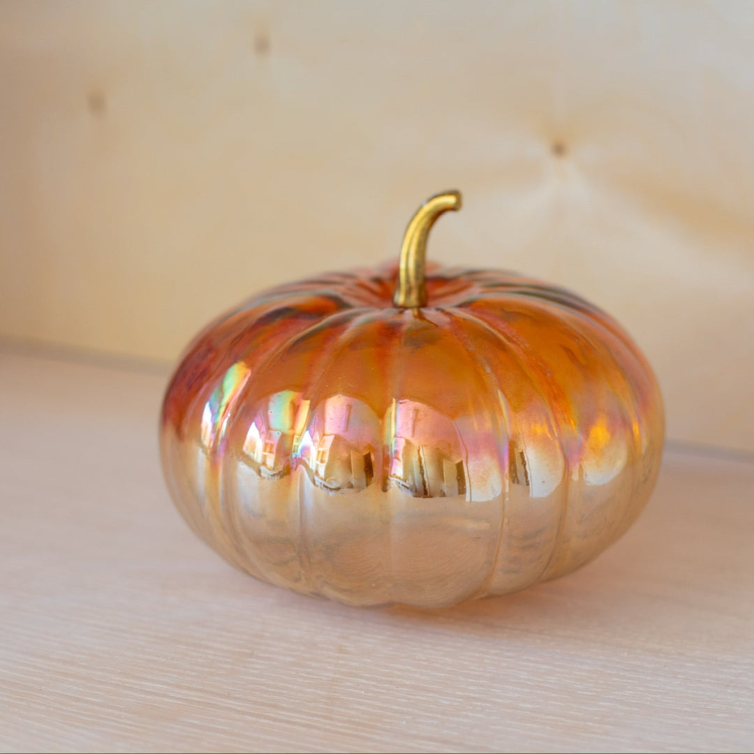 Glass pumpkin with gold stem on a wooden surface