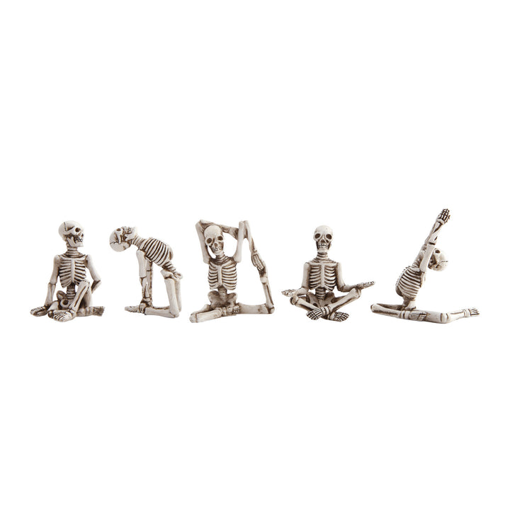 Five skeleton figures in various yoga poses on a white background