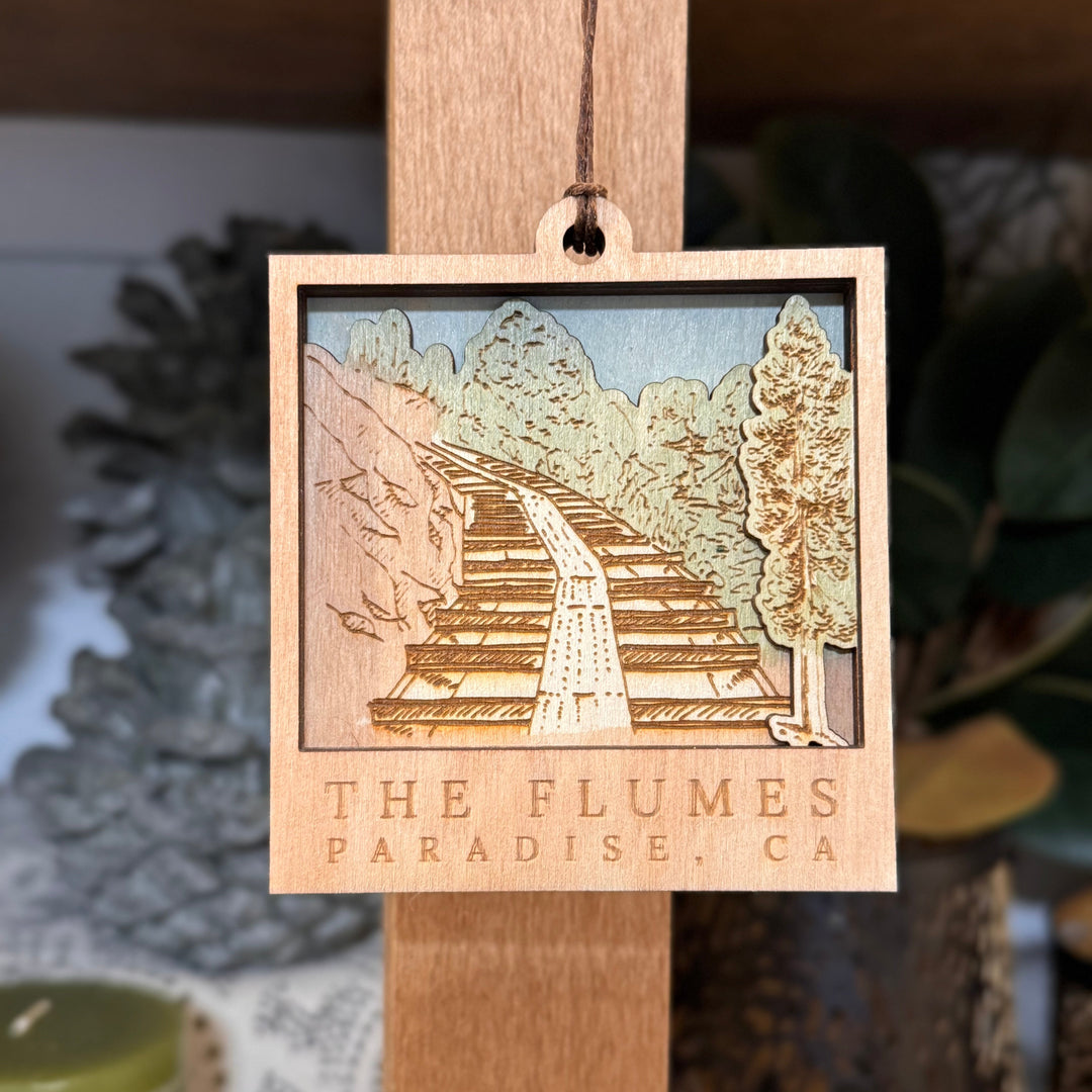 Decorative ornament with 'The Flumes Paradise, CA' on a wooden stand.