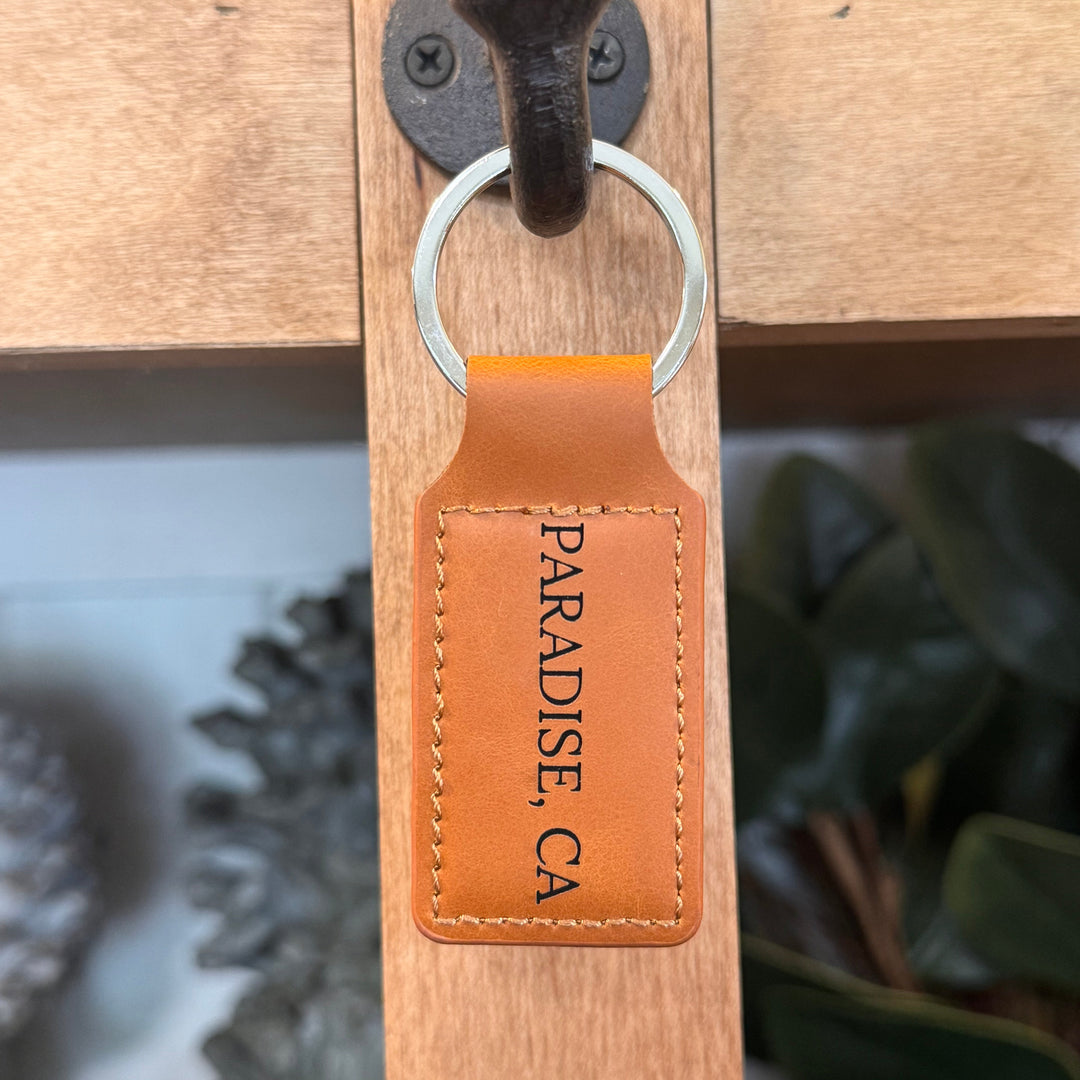 Keychain with 'Paradise, CA' on a wooden surface