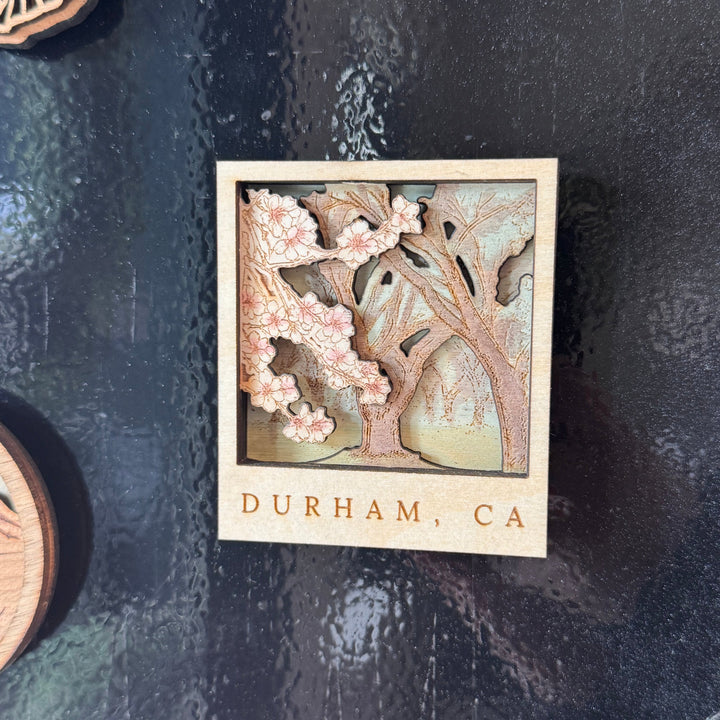 hand painted wooden magnet with blooming almond orchard scene, durham ca text