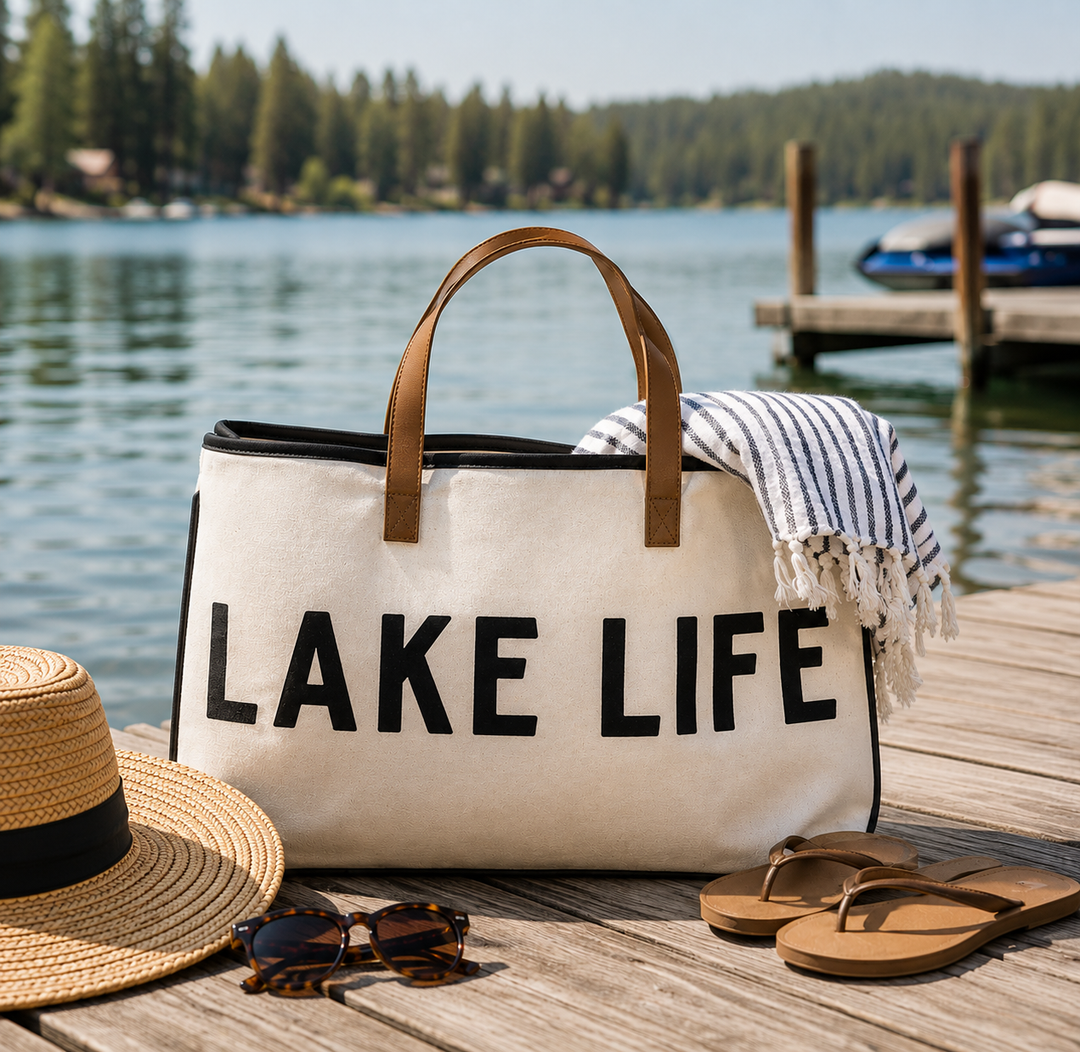 White tote bag with 'LAKE LIFE' text on a dock by a lake