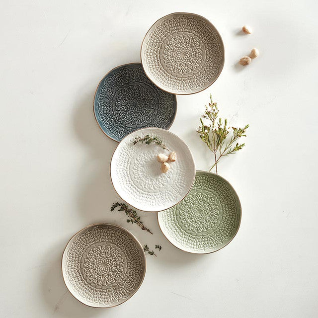 Set of five ceramic plates in various colors on a light background