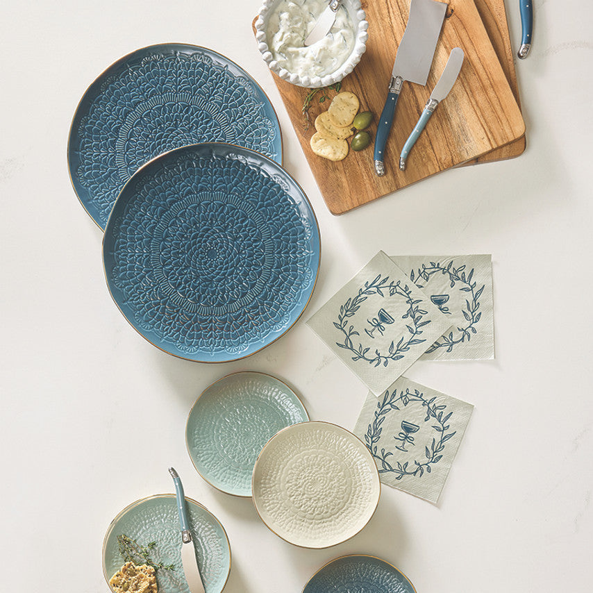 Collection of blue and white ceramic plates on a light surface with a cutting board and utensils.
