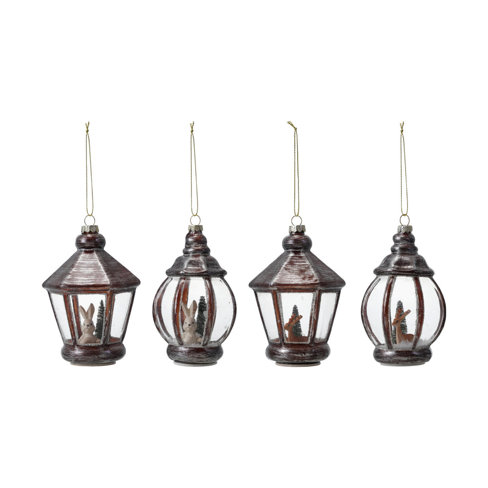 Four hanging lantern ornaments with Christmas scenes inside on a white background
