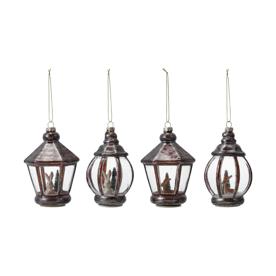 Four hanging lantern ornaments with Christmas scenes inside on a white background
