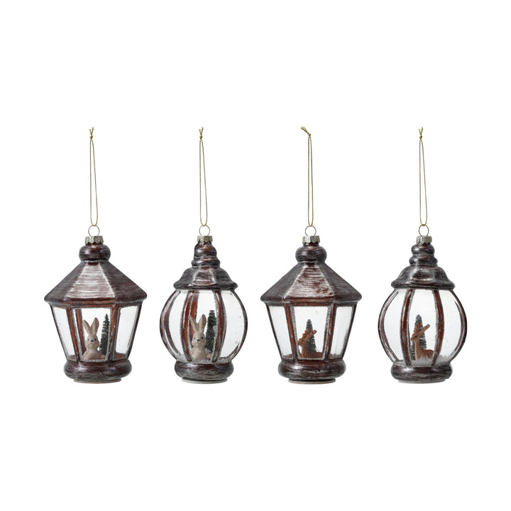 Four hanging lantern ornaments with Christmas scenes inside on a white background