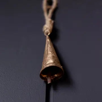 Close-up of a vintage-inspired tapered bronze iron bell ornament with rustic hanging loop.