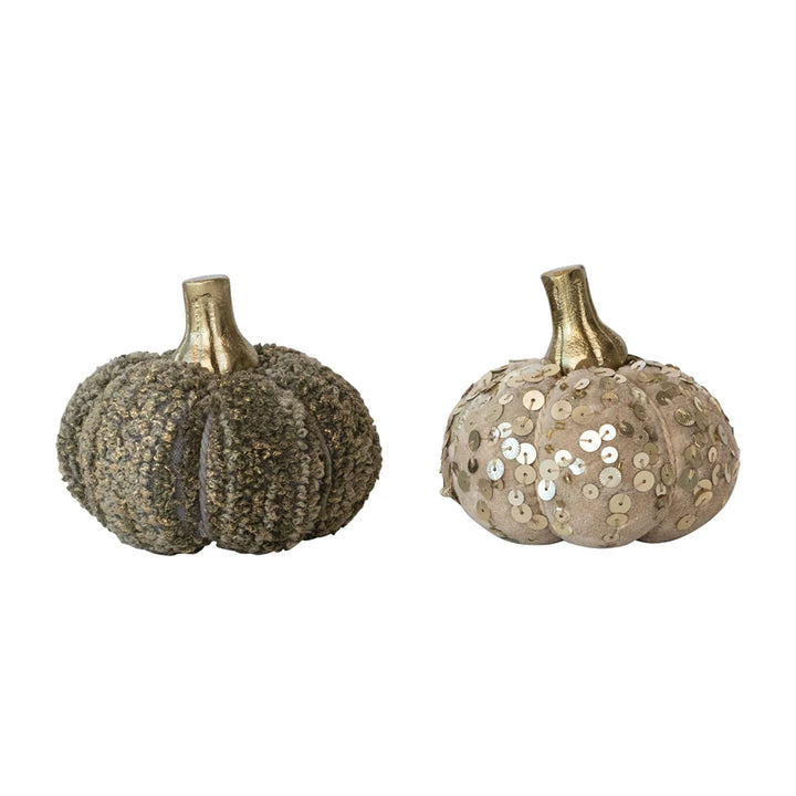 Two decorative pumpkins with sequin details on a white background