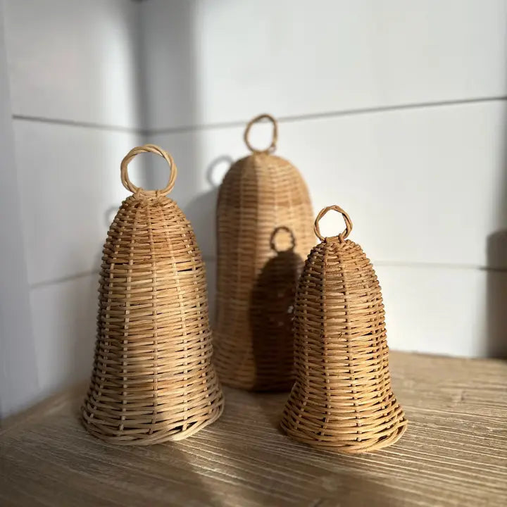 Three natural rattan decorative bells in small, medium and large sizes styled together on a shelf.