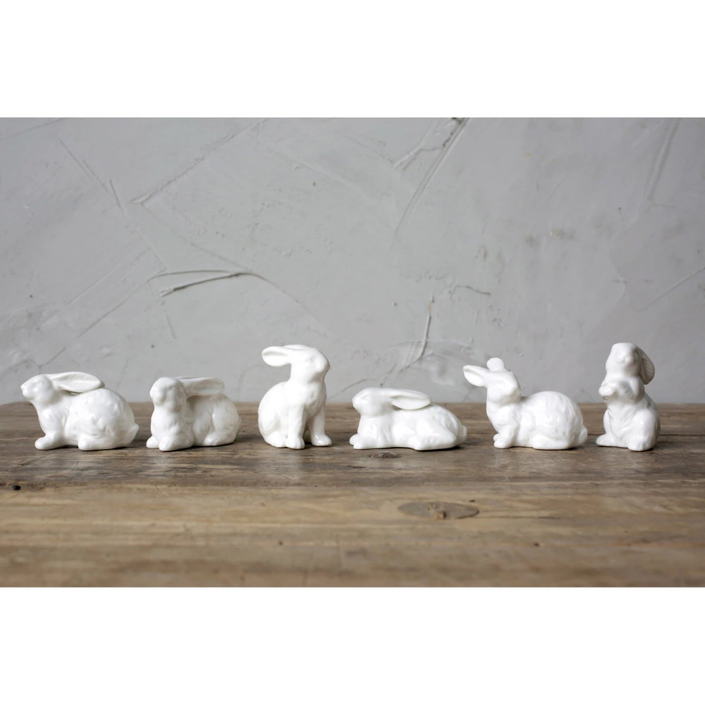 Set of white ceramic rabbit-shaped candle holders on a wooden surface with a gray background