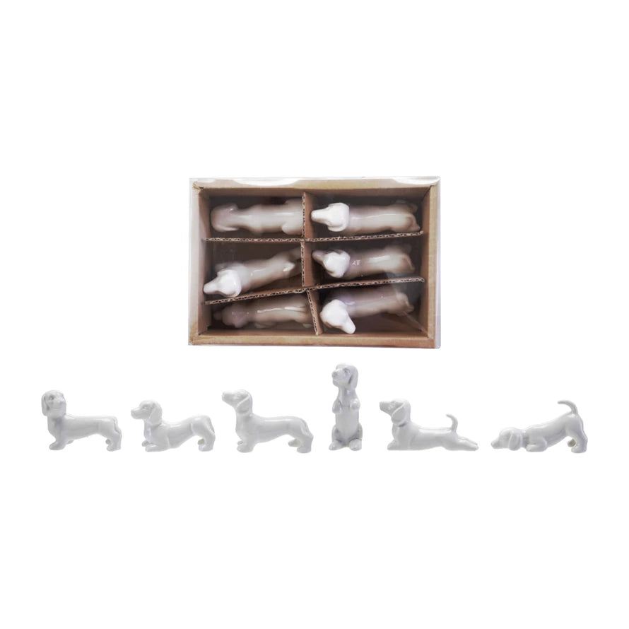 Set of white ceramic dog figurines with a wooden box containing similar figurines on a white background.