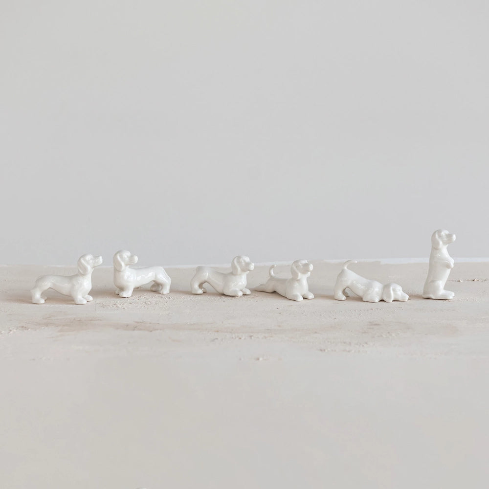 Set of white ceramic dog figurines on a light wooden surface with a white background