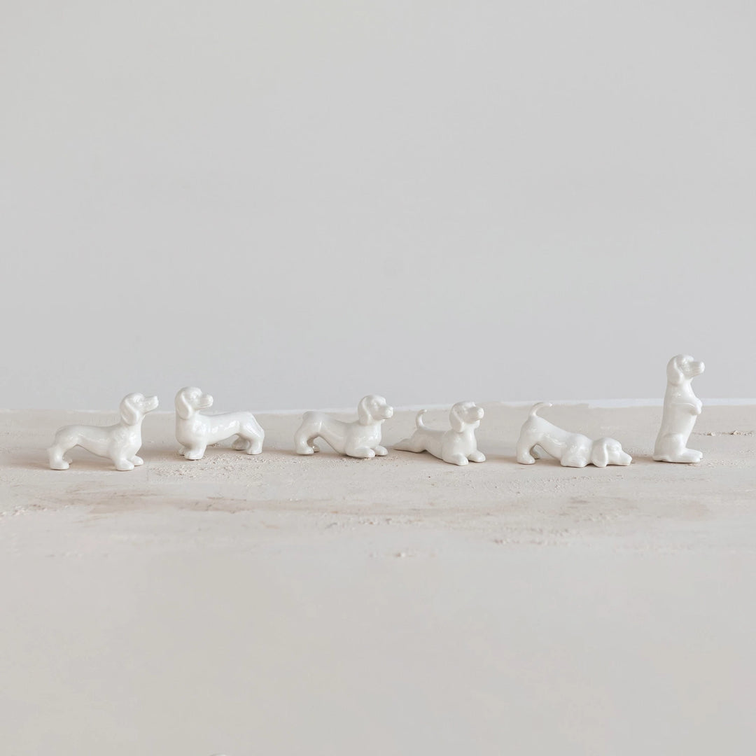 Set of white ceramic dog figurines on a light wooden surface with a white background