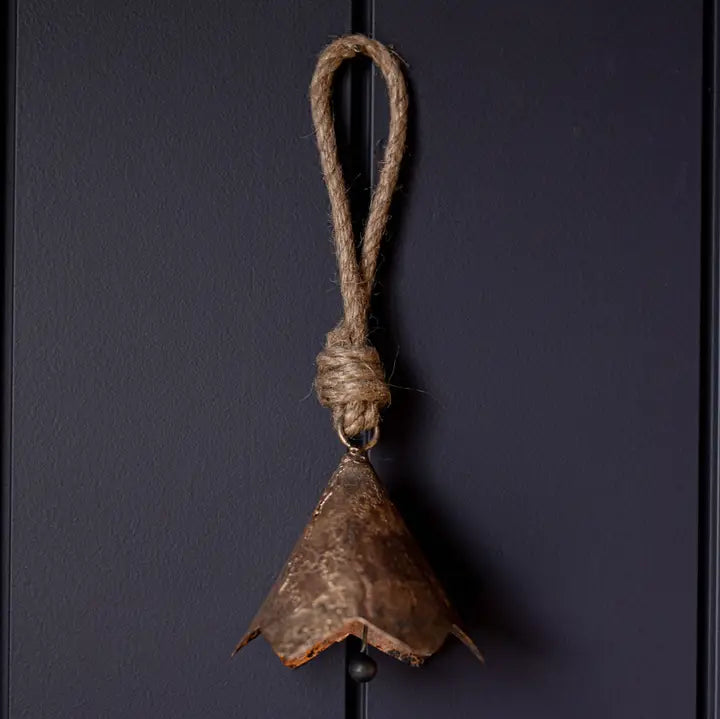 Vintage-inspired bronze scalloped iron bell ornament with natural-look hanging loop against a dark background.