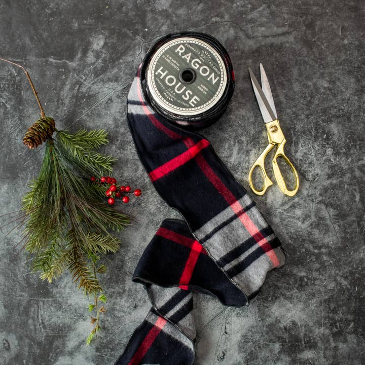 Black tartan wired ribbon with red and white plaid lines beside evergreen sprigs