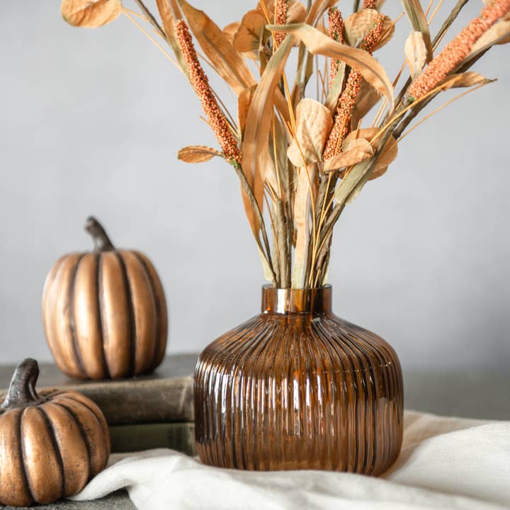 Brown ribbed glass vase with rounded shoulders and a short narrow neck, styled with dried stems
